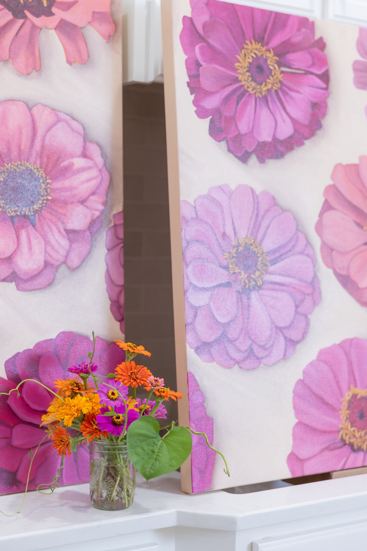 Garden Party II and a companion floral painting displayed on a white counter beside a jar of fresh flowers.