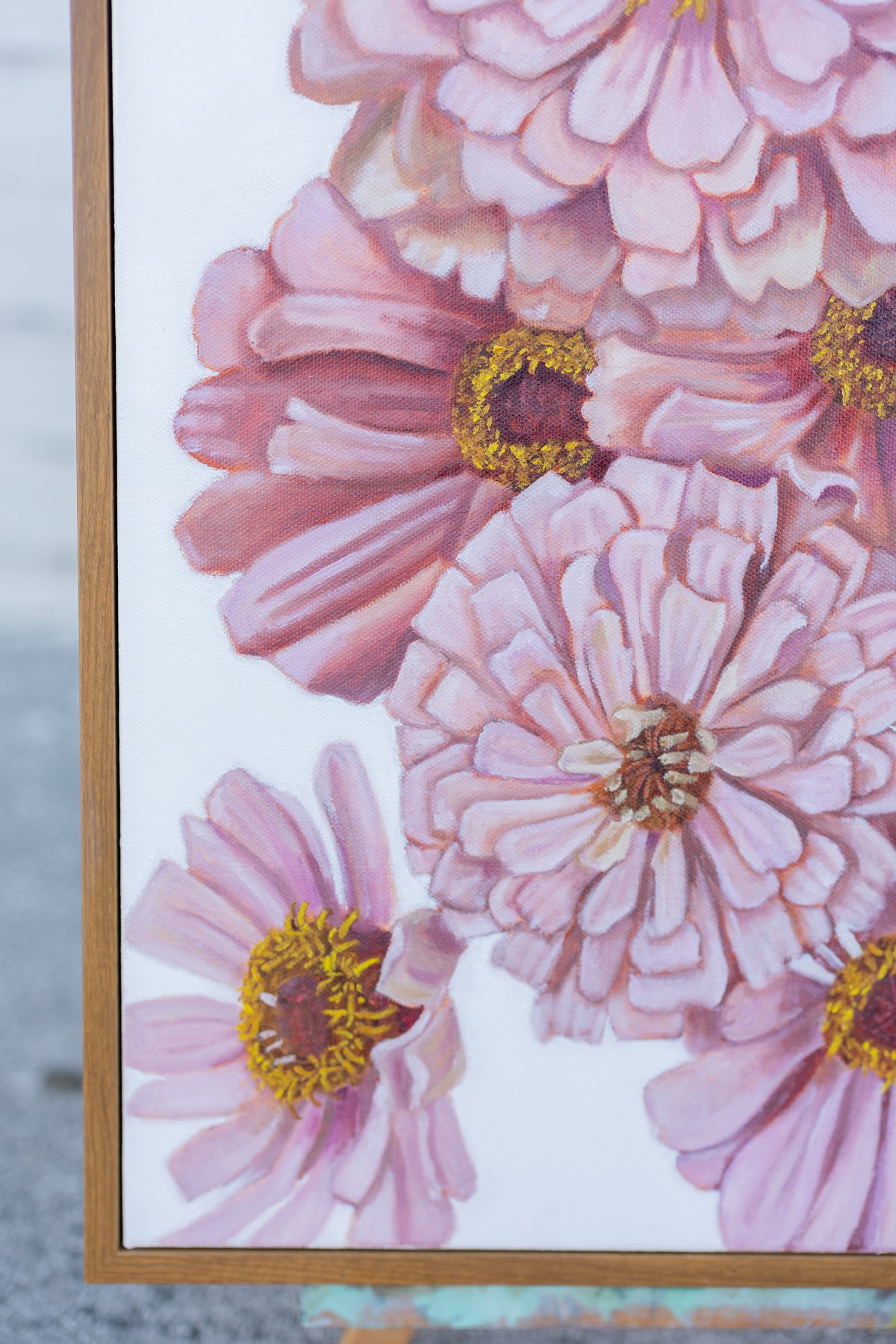 Close-up of Spring Zinnias showing pink flowers and the lower-left corner of its wooden frame.