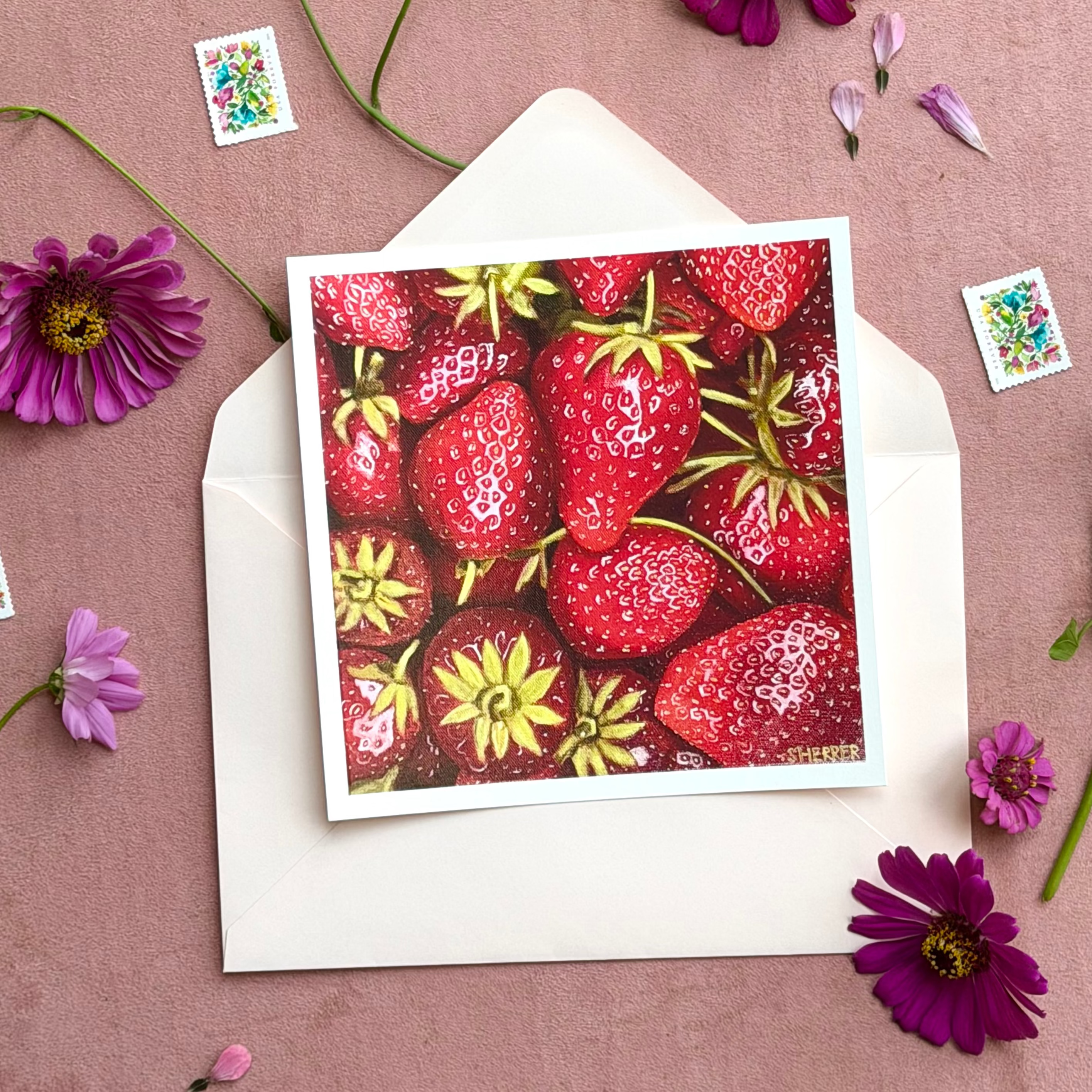 Example strawberry art print on a white envelope, surrounded by purple flowers and postage stamps.