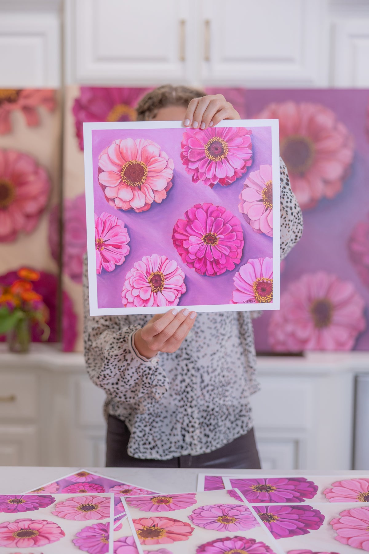 Caroline Sherrer holding Bold Blooms Print up in front of her face.