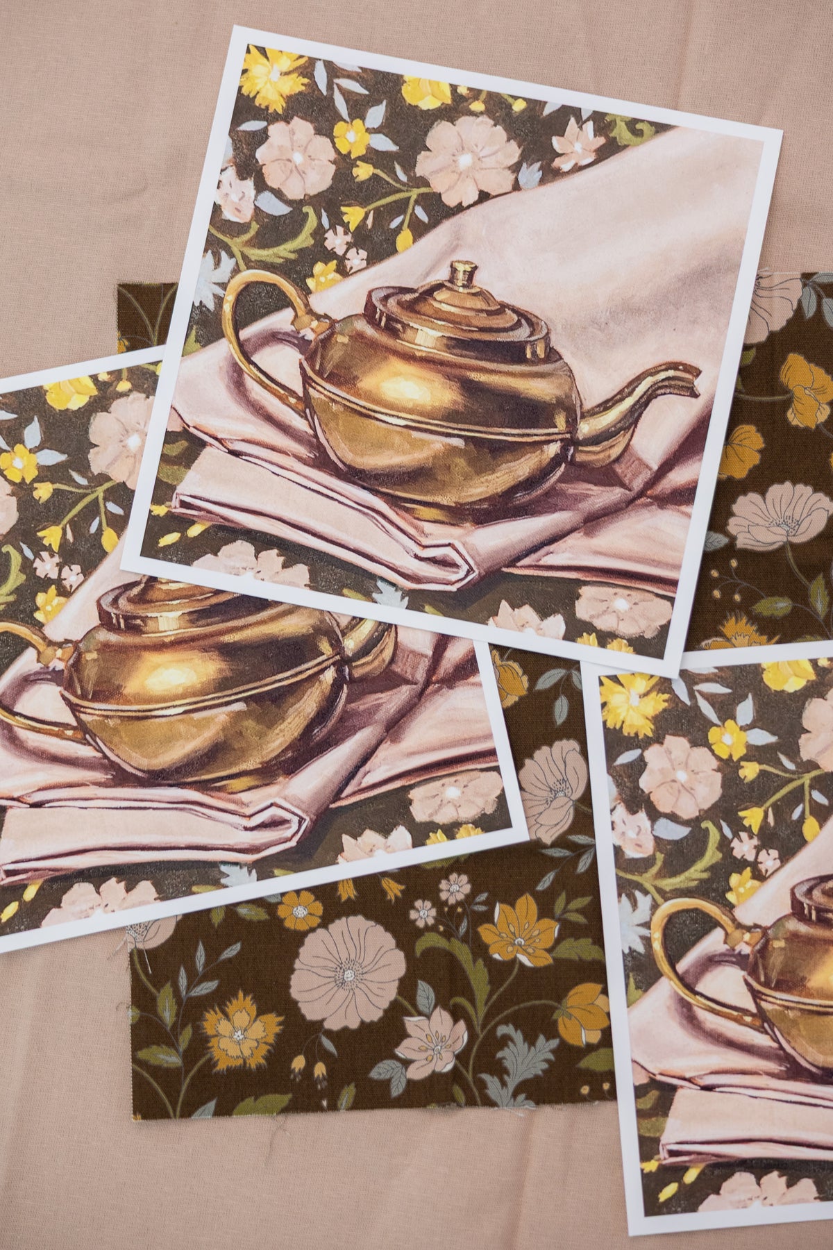 Close-up of overlapping white-bordered Kettle on Florals prints, showing a brass kettle against brown floral fabric.
