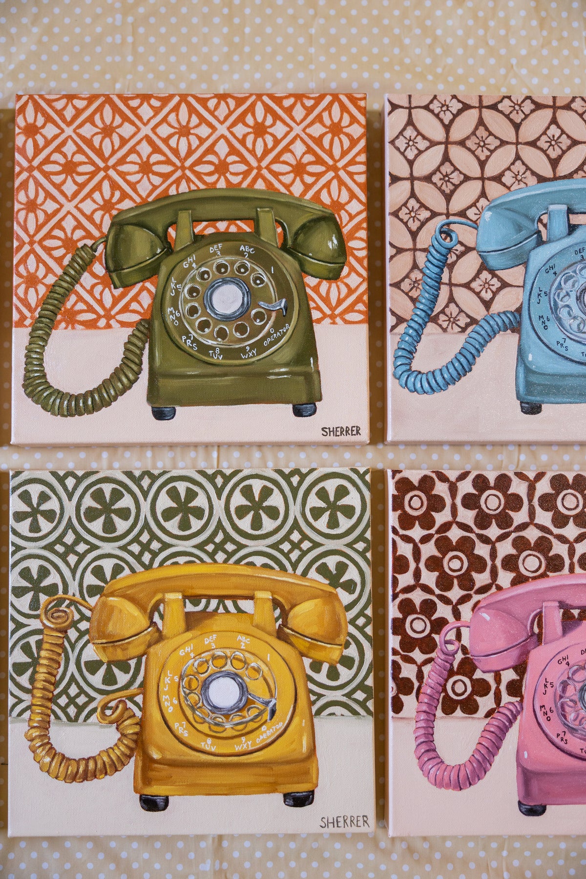 Close-up of green and yellow rotary-telephone paintings with portions of blue and pink telephone paintings beside them.