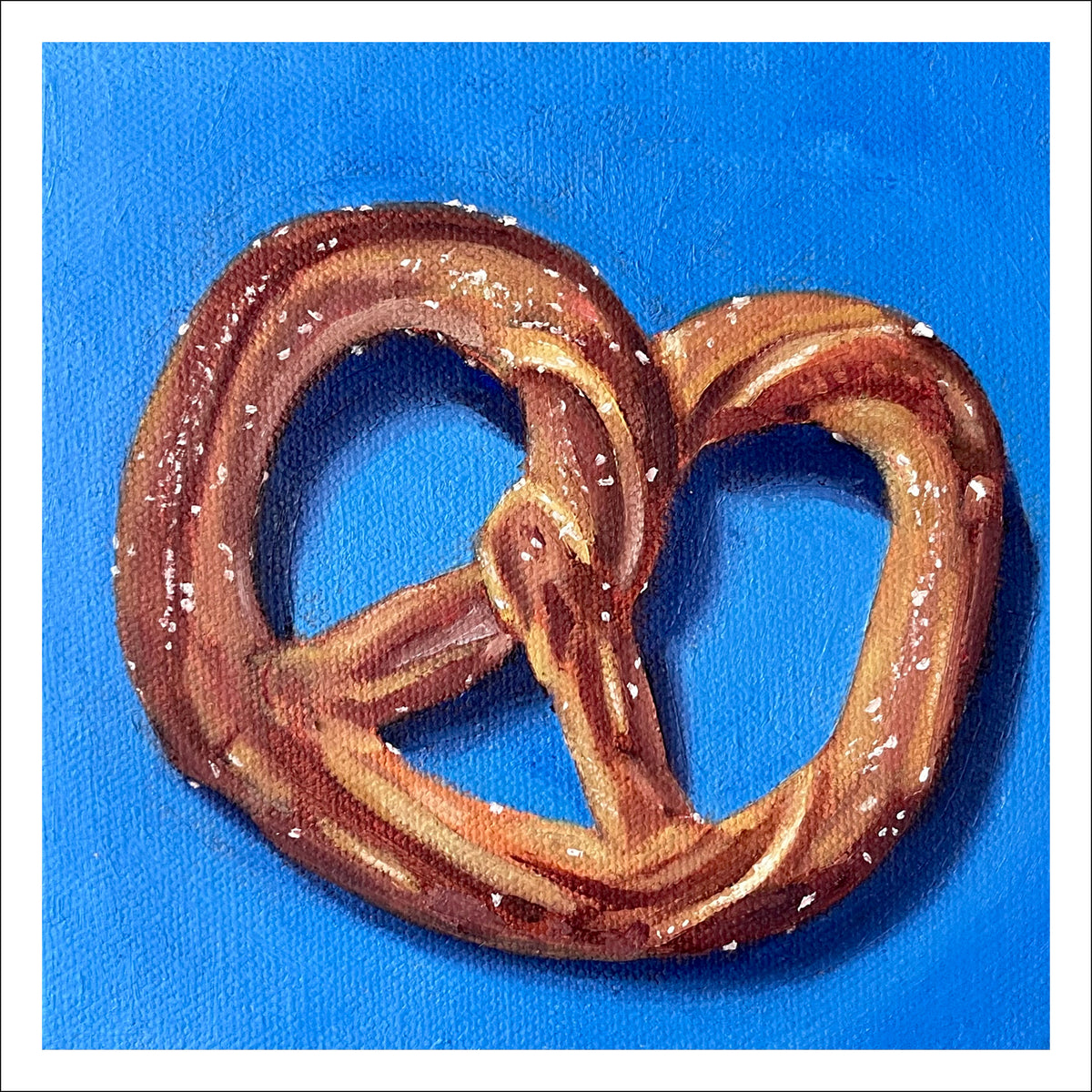 Pretzel fine art print by Caroline Sherrer, featuring a salted pretzel resting on a royal blue background.